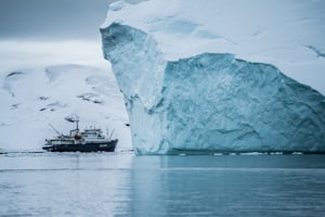 Petit navire d'expédition au pied d'un iceberg