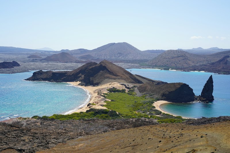 Le rocher Pinnacle et les deux plages de l'île Bartolomé vus du sommet de l'île, avec les volcans de l'archipel à l'arrière-plan